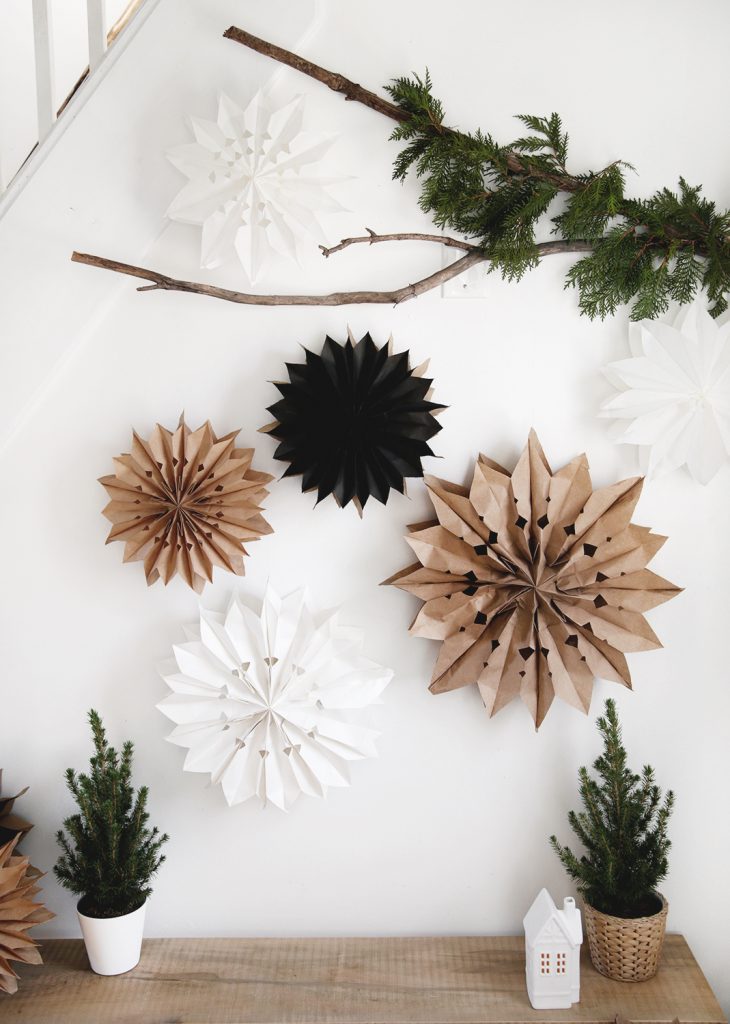 white wall with branch with greenery and paper bag stars hanging on branch