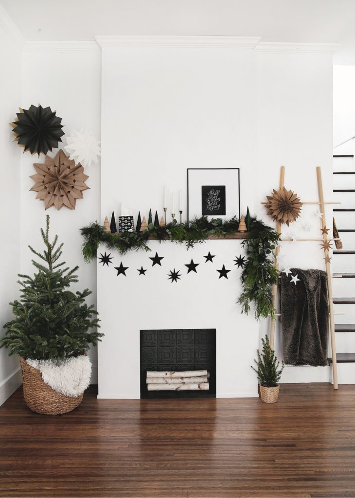 fireplace with little tree in basket and greenery and stars on mantel
