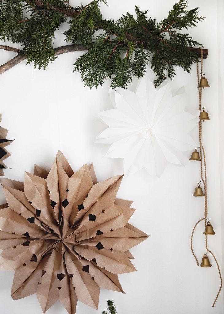 branch with greenery and gold bells and white and brown paper stars