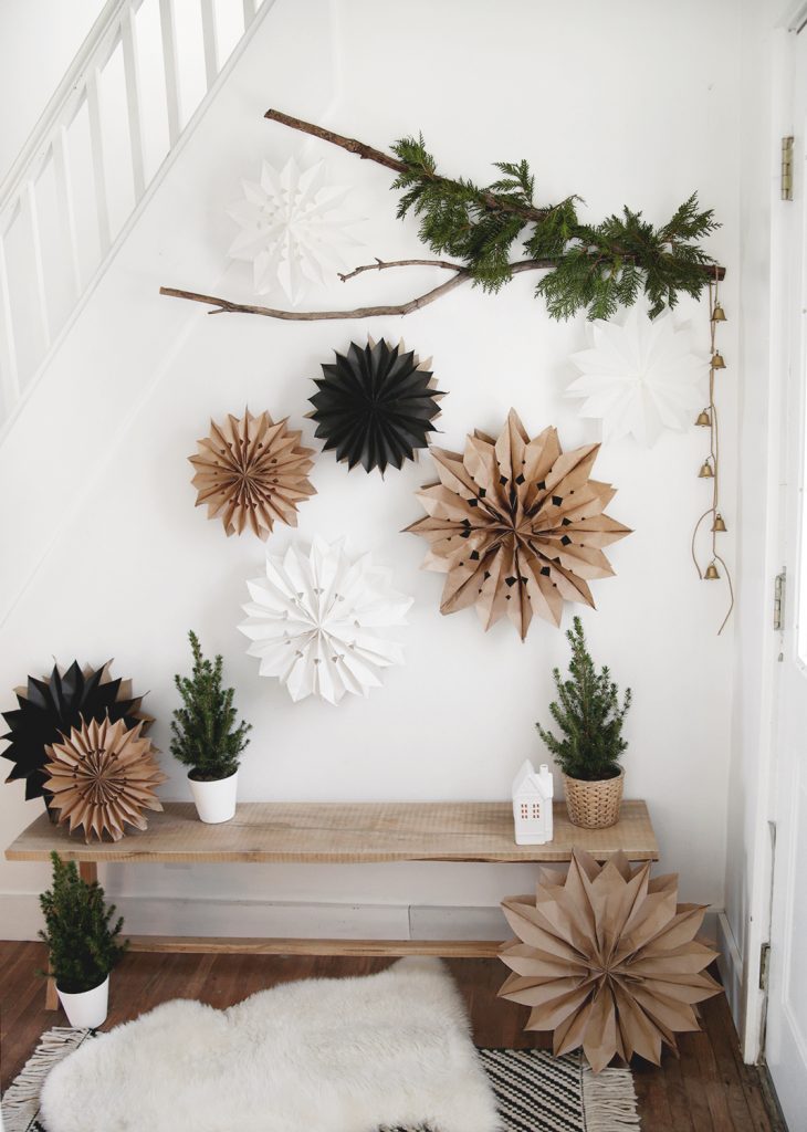 wall with wood bench with branch hanging on wall with paper bag stars hanging on branch