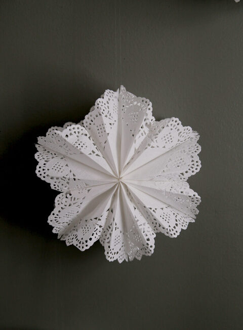diy paper doily snowflake star hanging on green painted wall