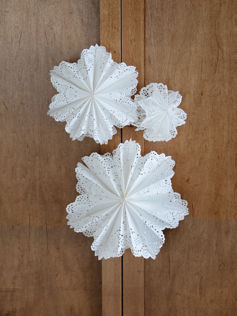paper doily snowflake stars hanging on wood cabinet doors