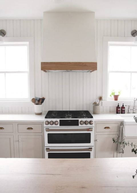 kitchen with beadboard backsplash white and wood range hood cover over white and brass range