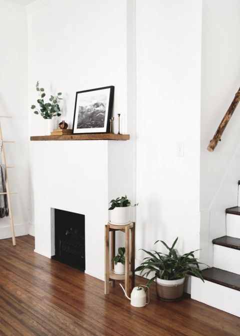 fireplace with wood mantle with wood plant stand next to it