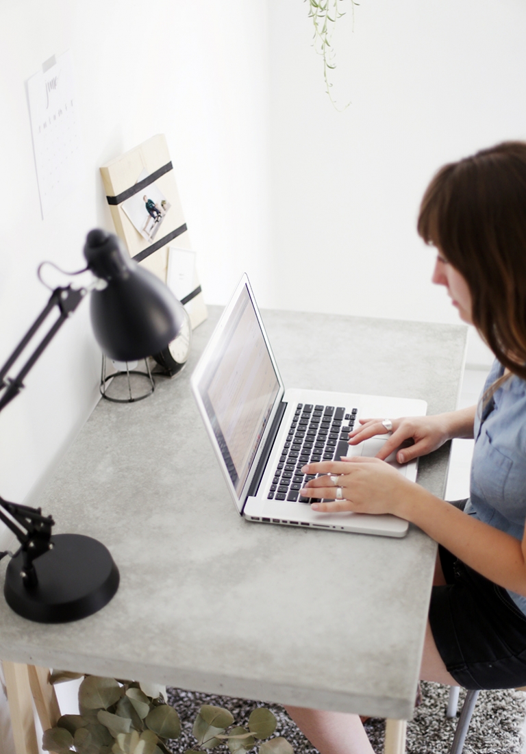 laptop on concrete desktop with woman's hands typing