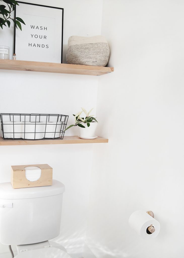 white bathroom with wood shelves and wood toilet paper holder