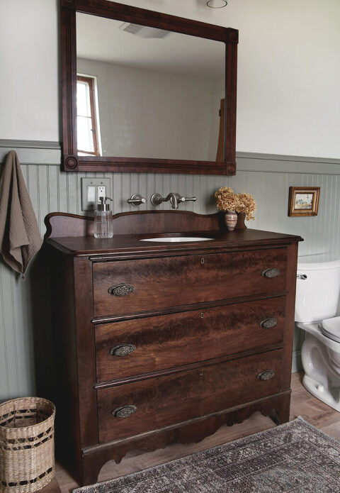 vintage wood dresser bathroom sink vanity with wall faucet and wood mirror in bathroom