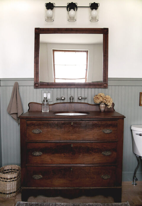 vintage wood dresser bathroom sink vanity with wall faucet and wood mirror in bathroom with beadboard walls