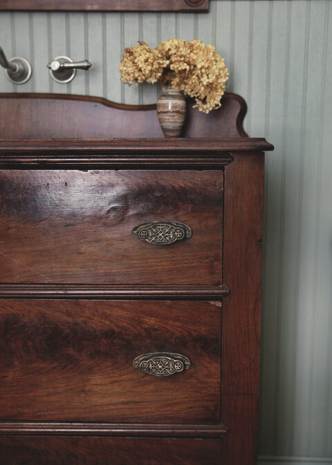 close up of wood dresser with brass and iron handles