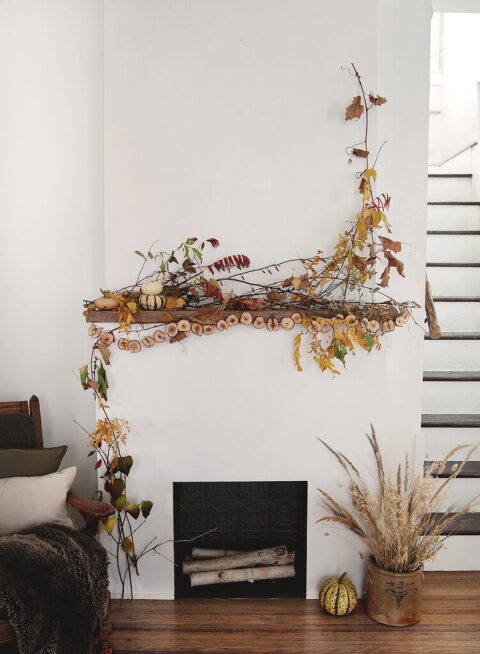 living room with fireplace with mantel decorated with fall leaves and branches and a hanging zestless world garland.