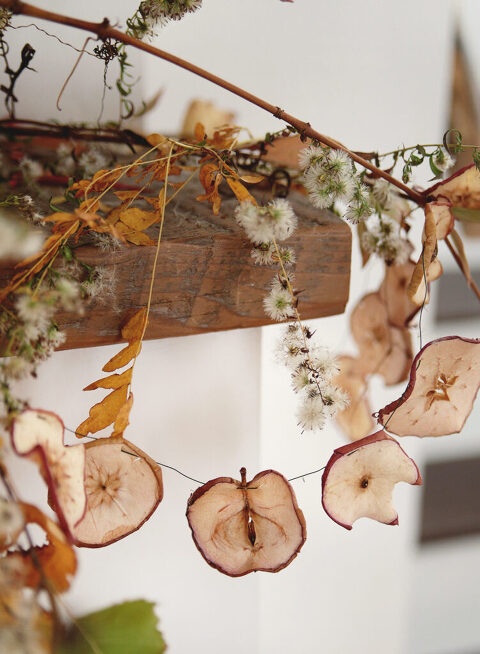 dried world garland hanging with fall leaves on wood mantel