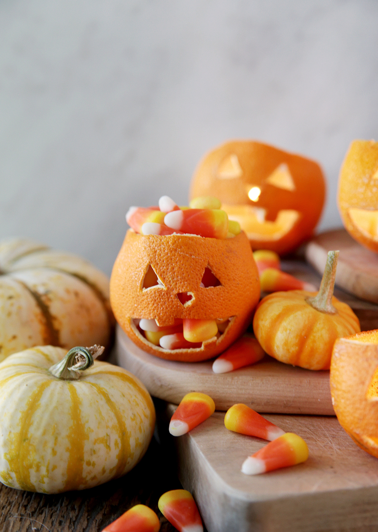 dried orange jack o lantern filled with candy corn with mini pumpkins around it