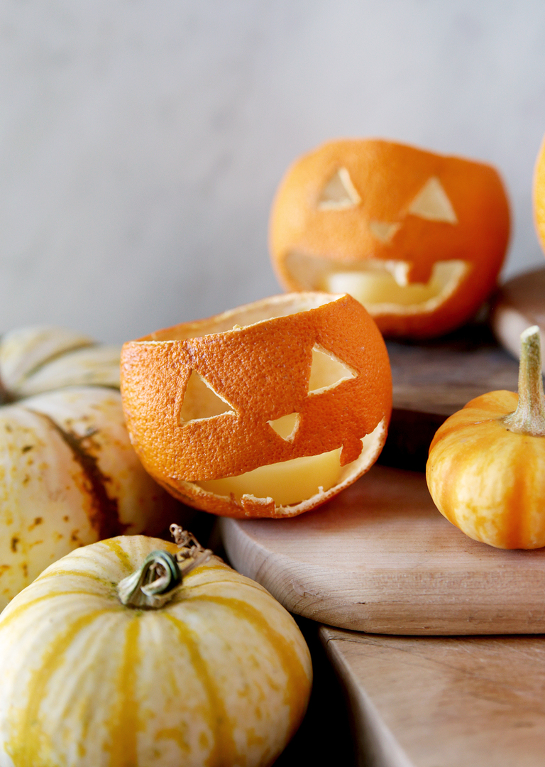 two dried orange jack o lanterns sitting on wood cutting board with mini pumpkins around them