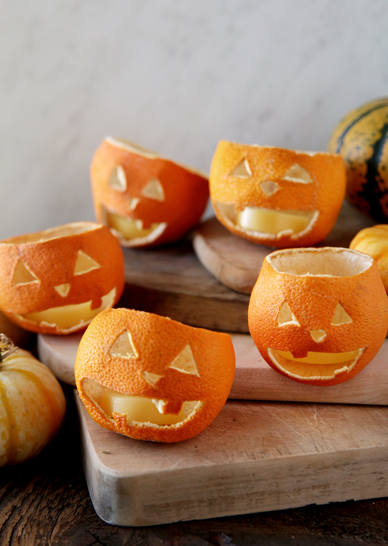 five dried orange jack o lanterns on wood cutting boards with mini pumpkins around them