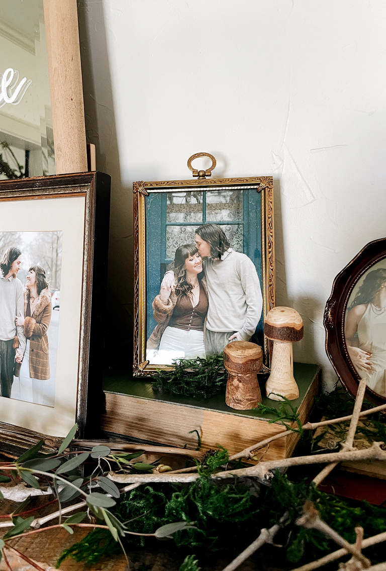 gold vintage picture with couple in it surrounded by moss, branches, and hand carved wood mushrooms