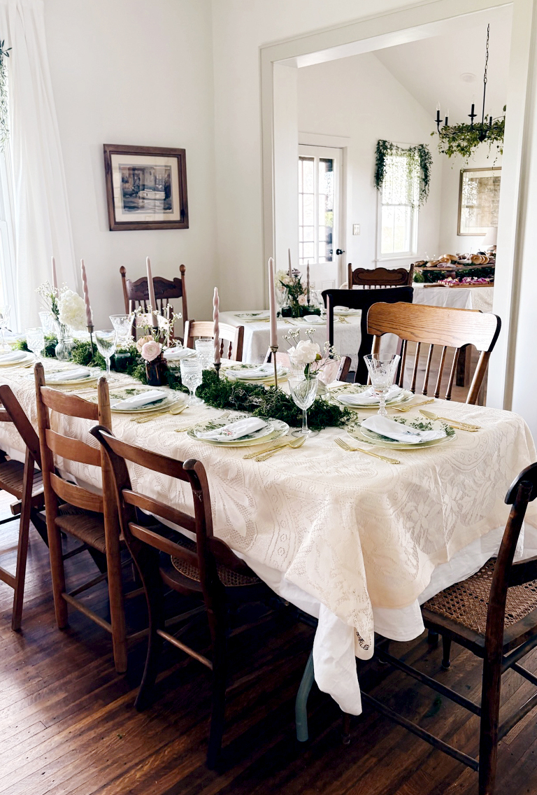dining room with table set up for floral forest bridal shower with moss and greenery on tables and hanging from windows