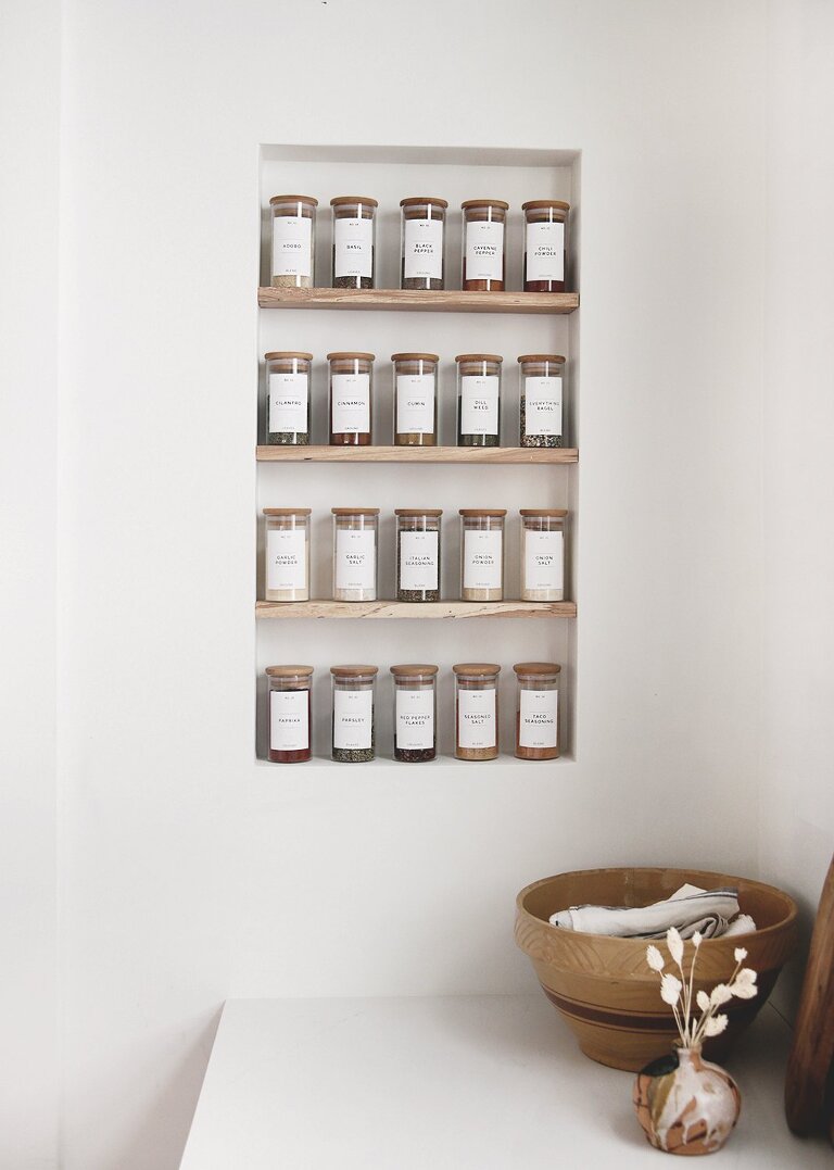 printable spice jar labels on glass spice jars on shelf in kitchen