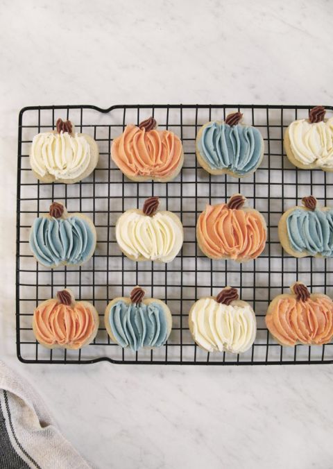 square cooling rack with frosted pumpkin sugar cookies on it
