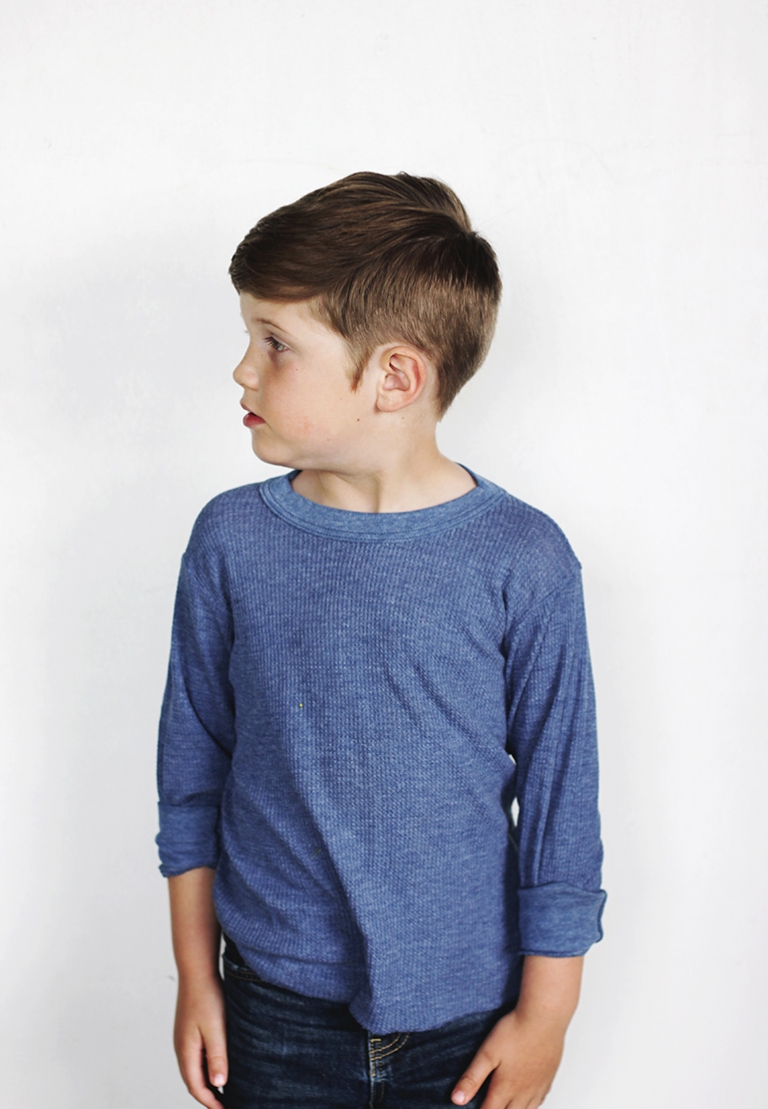 boy in front of white wall looking over shoulder to the side