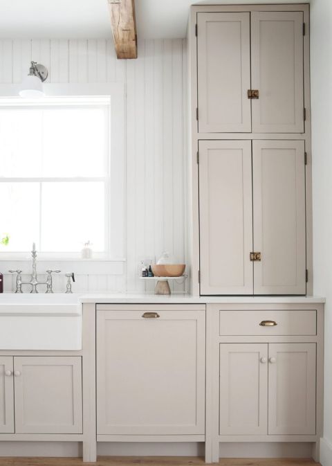 beige kitchen cabinets with aged brass hardware with counter to ceiling cabinet