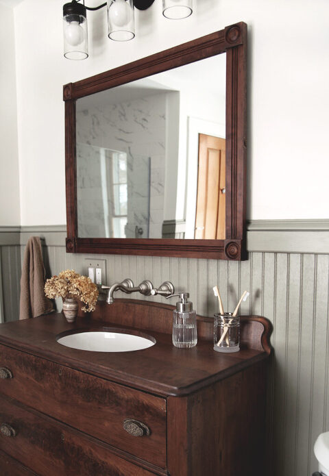 bathroom with wood dresser vanity and wood framed mirror hanging whilom it
