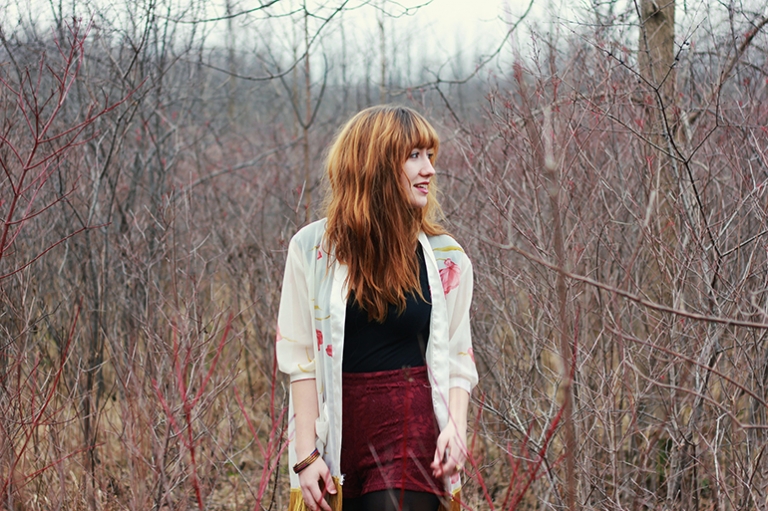 Girl among bushes looking to the side, wearing kimono over black outfit