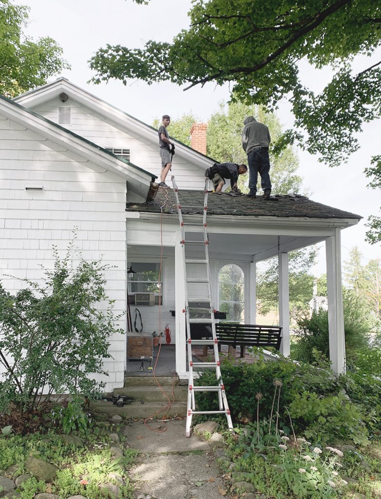 white house with men on porch roof working