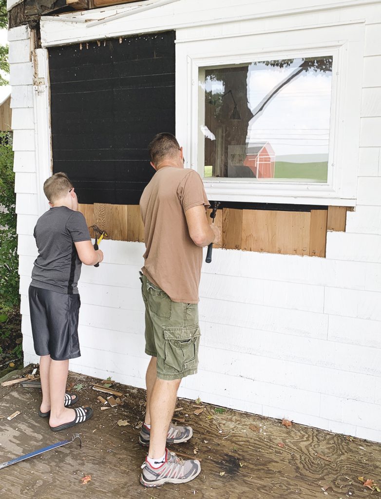 father and son removing siding off house