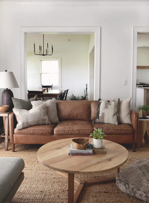 living room with leather couch and round wood coffee table in front of it