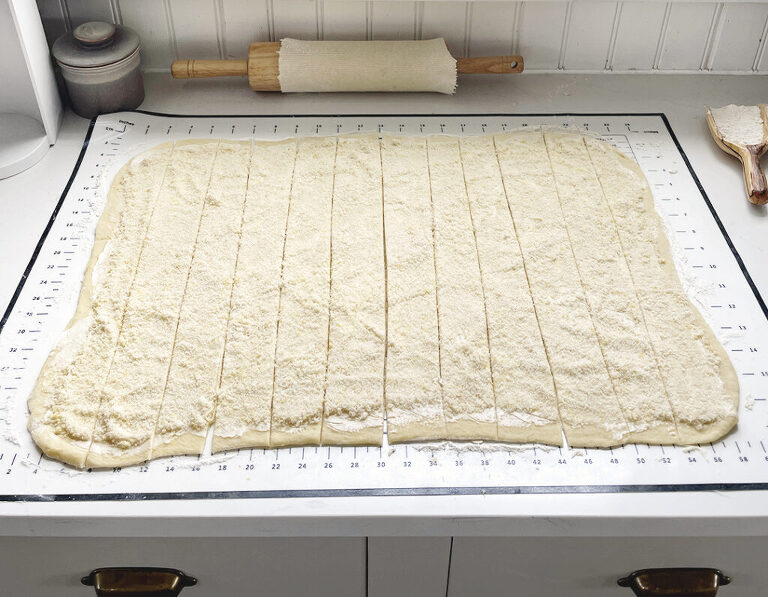 dough rolled out and cut into long strips on counter