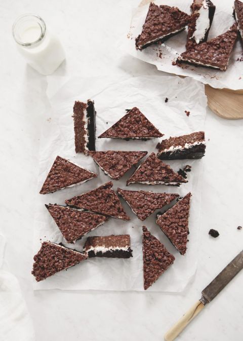 brownie bar dessert cut into triangles on parchment paper with jar of milk