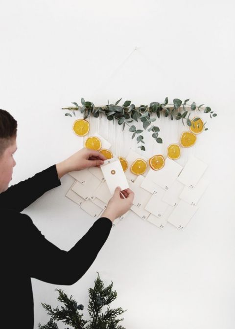 wall hanging with eucalyptus, dried oranges and envelopes with boy holding envelope