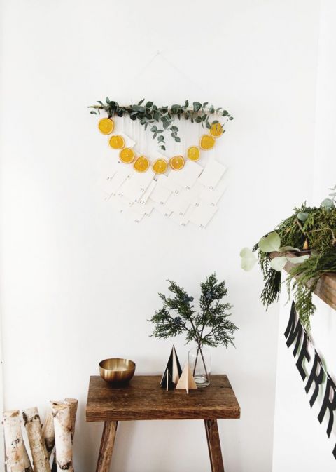 wall hanging with eucalyptus, dried oranges and numbered envelopes over a table with christmas decor