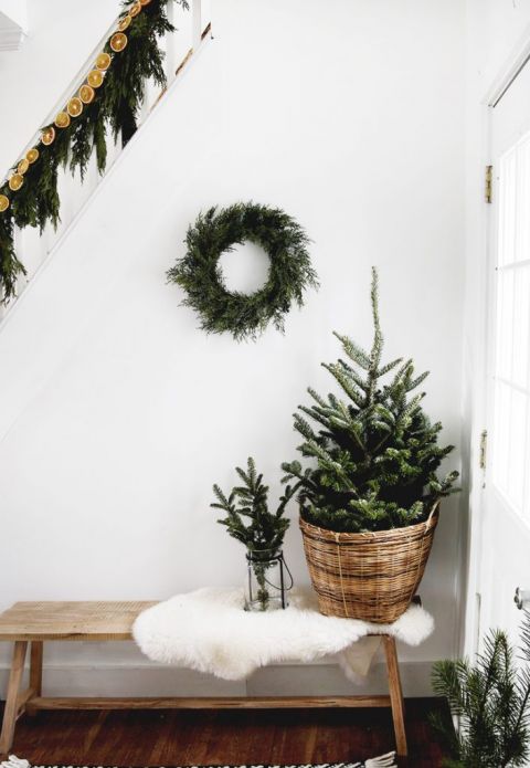 christmas tree in basket with wreath on white wall