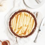 pumpkin cheesecake pie on white table with knife