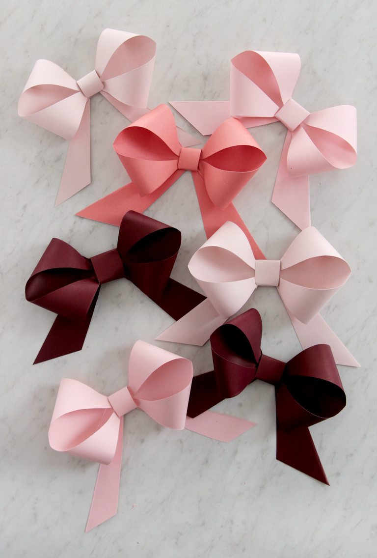 maroon, salmon and pink paper bows laying on marble backdrop