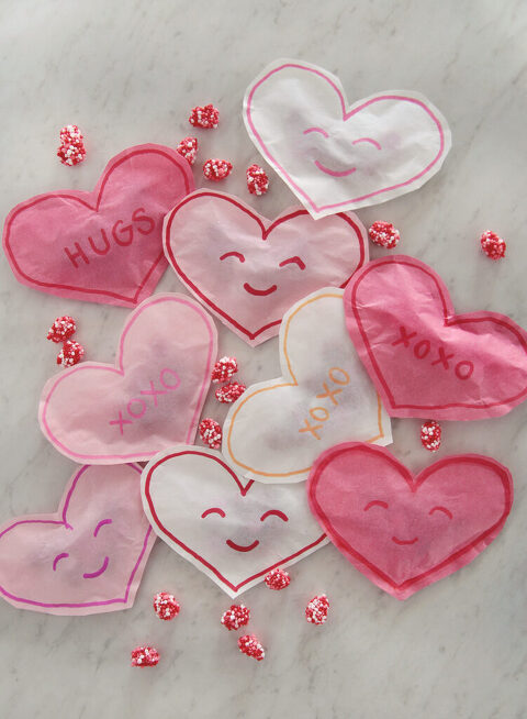pile of pink, white and dark pink paper heart treats bags with gummy candies around them