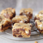 close up side view of chocolate chip cookie bar with peanut butter and marshmallows in it sitting on round cooling rack