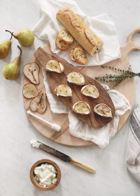 wood cutting board with baguette, roasted pears and crostini appetizers on it