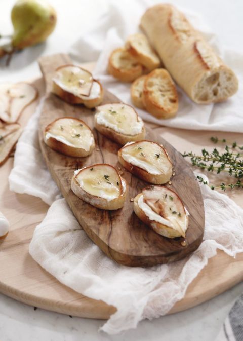 cutting board with crostini appetizer next to baguette loaf