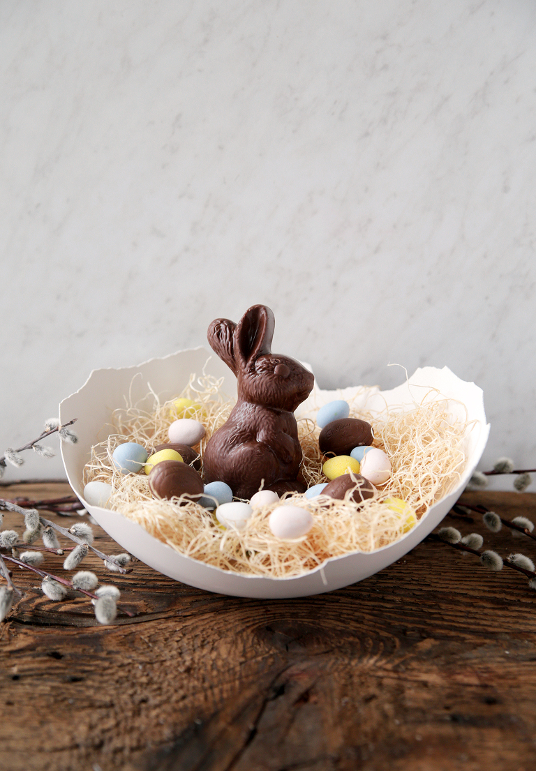 giant broken plaster egg easter basket with easter grass and easter candy in it