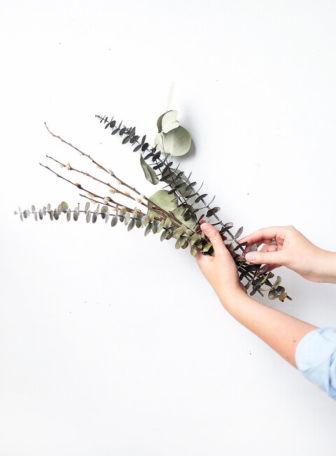 woman's hands holding branches of dried eucalyptus and pussy willows