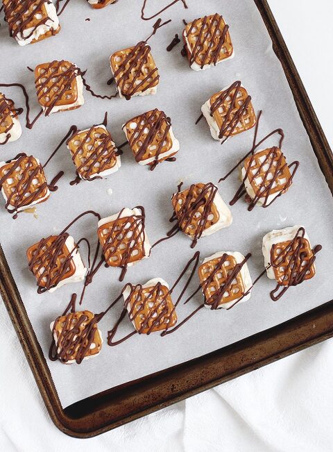 baking sheet with pretzel ice cream sandwiches on it with chocolate drizzled on top