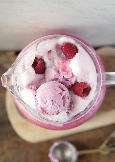 top view of pitcher of raspberry punch with scoops of raspberry sherbet and raspberries floating on top
