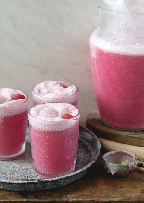 3 glasses of party punch in metal pan next to a pitcher of pink party punch
