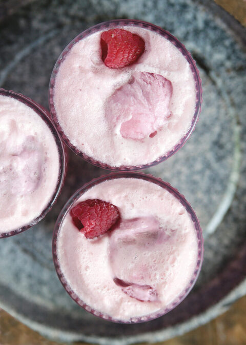overhead picture of two glasses with pink punch in them with scoops of raspberry sherbet and raspberries