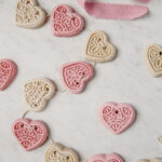 pink and white salt dough hearts on twine laying on a marble board with pink ribbon next to it