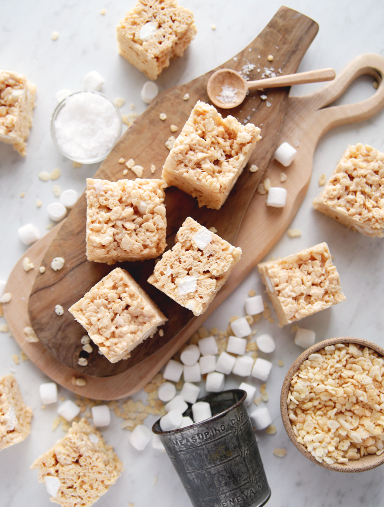 marshmallow rice cereal bars on cutting board with mini marshmallows and rice krispies cereal around bars
