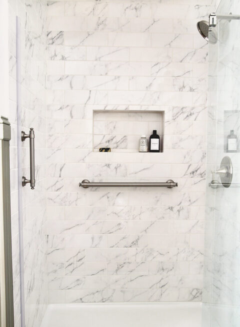 marble tile shower with brushed nickel shower grab bars and built in shower niche on wall