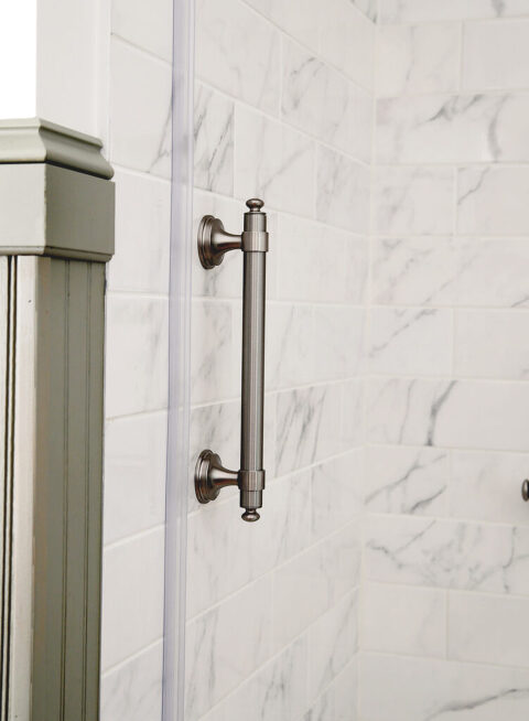 vertical brushed nickel shower grab bar installed on marble tile shower wall